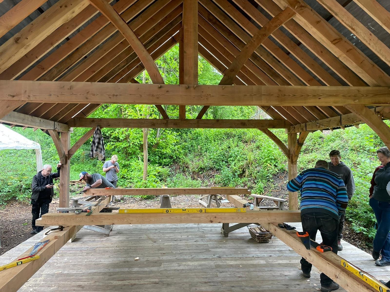 Students learning traditional timber framing skills during a hands-on course at Tree Tops and Train Tracks in North Wales