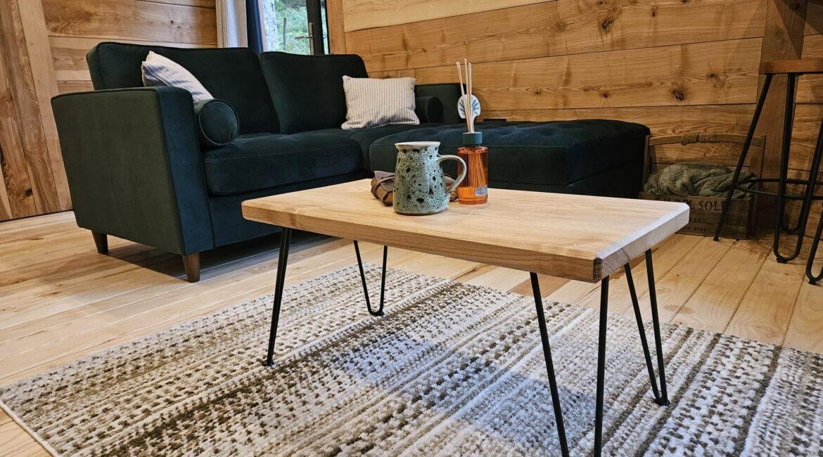 Cosy living area with handmade ash furniture and timber interior inside the Toad Hideout woodland glamping cabin in North Wales