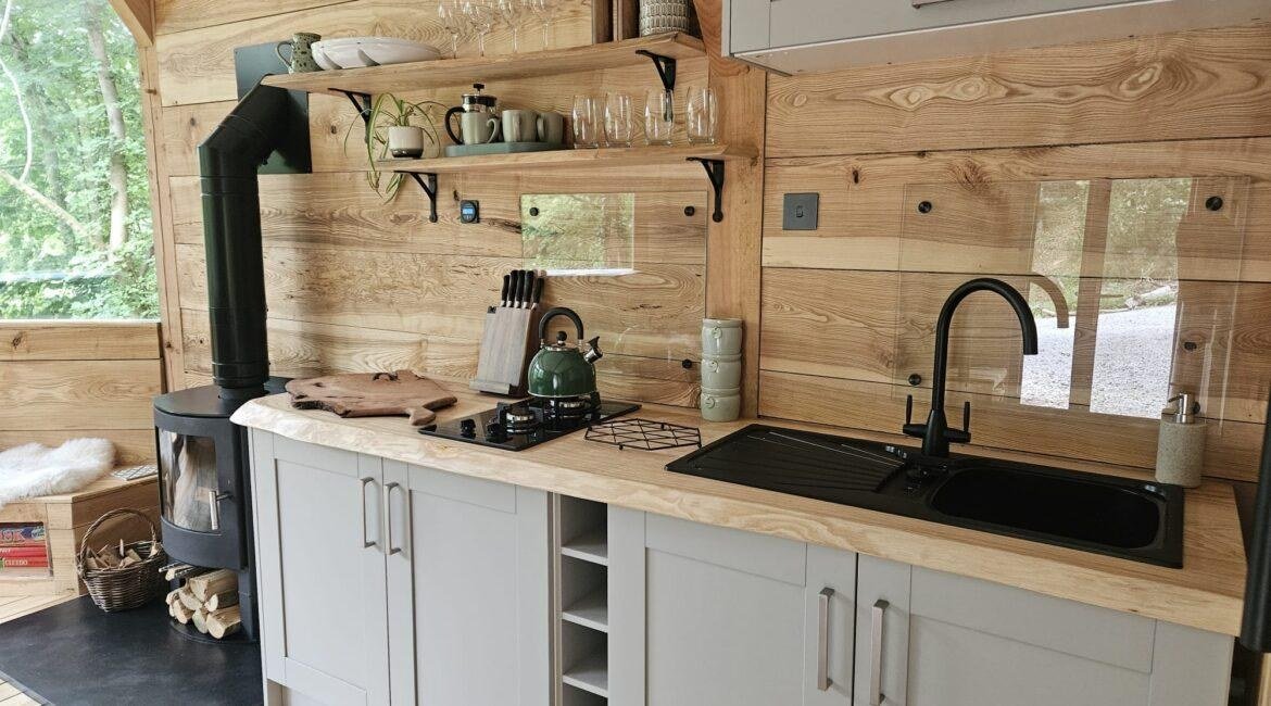 Handcrafted kitchen and wood-burning stove inside the Toad Hideout woodland cabin at Tree Tops and Train Tracks in North Wales