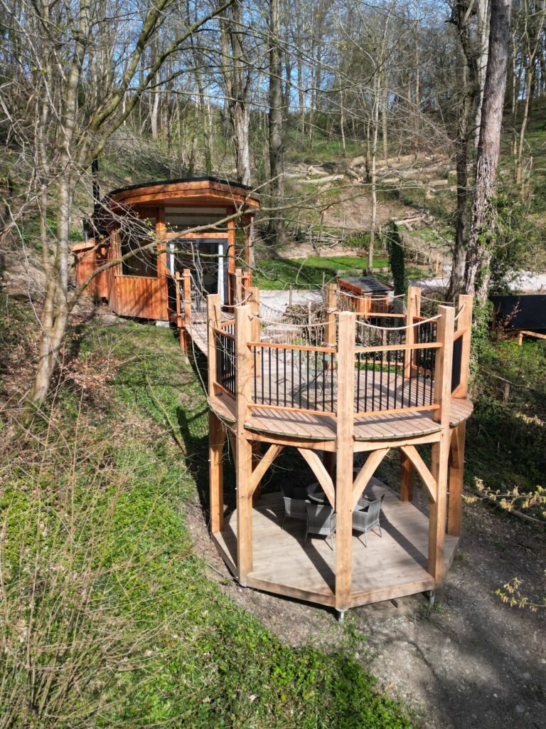 Toad Hideout woodland glamping cabin with two-storey timber deck surrounded by ancient woodland at Tree Tops and Train Tracks, North Wales