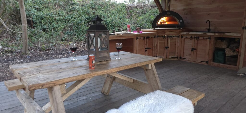 Wood-fired pizza oven and covered outdoor kitchen for guests enjoying a woodland glamping break in North Wales