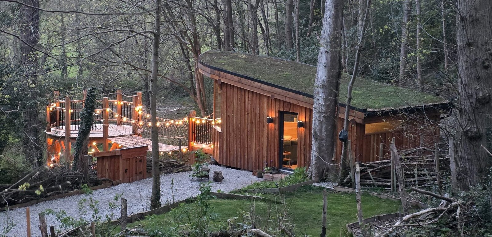 Toad Hideout woodland glamping cabin with living roof, rope bridge and private raised deck at Tree Tops and Train Tracks, North Wales