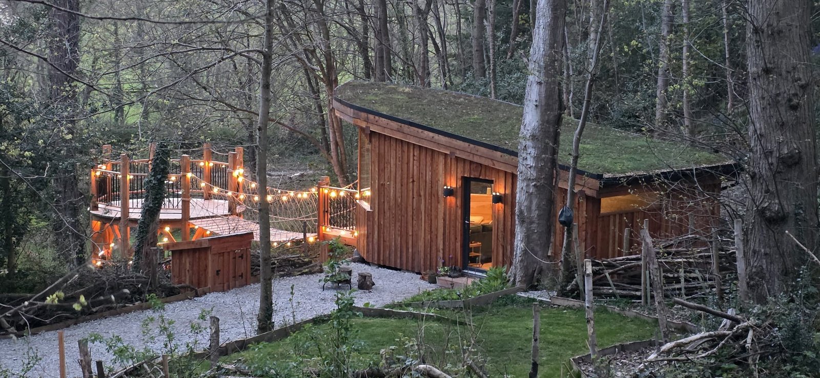 Toad Hideout woodland glamping cabin with living roof, rope bridge and private raised deck at Tree Tops and Train Tracks, North Wales